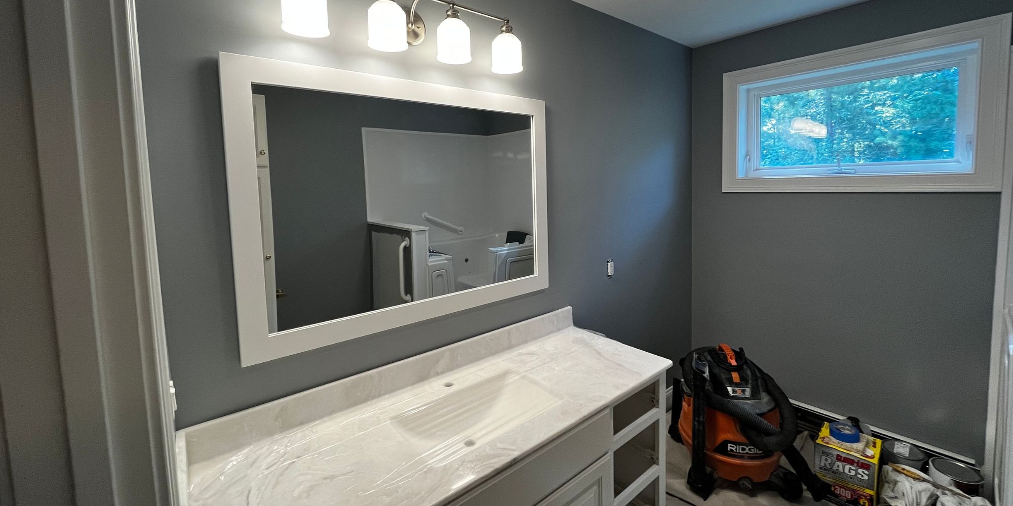 Bathroom remodel with porcelain tile floors and solid-surface vanity top under construction in Durham, NH