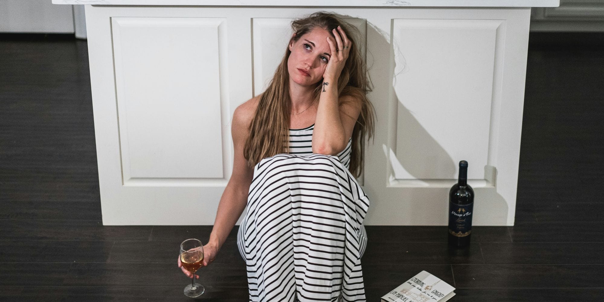 Woman sits next to a kitchen island looking worried from problems with her kitchen remodel in Portsmouth, NH