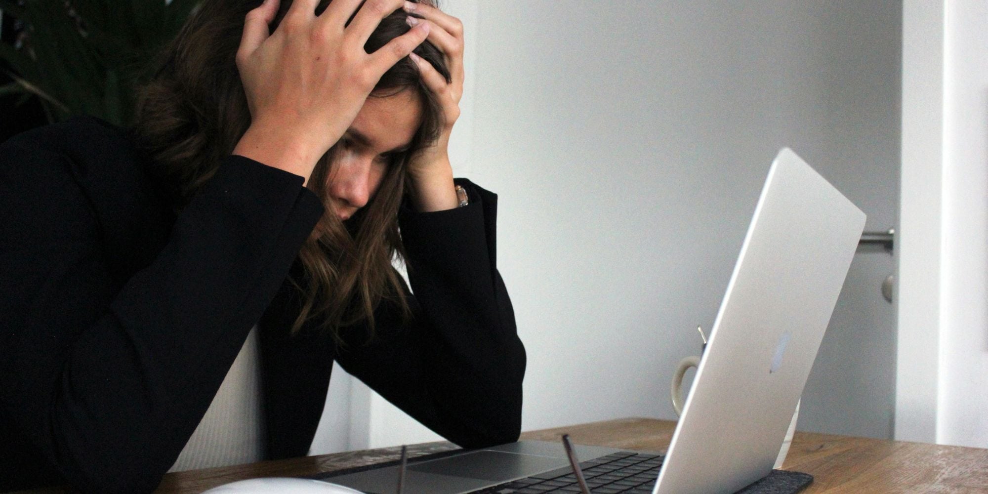 Stressed woman holds her head in front of a laptop worried about bathroom remodel problems in Exeter, NH
