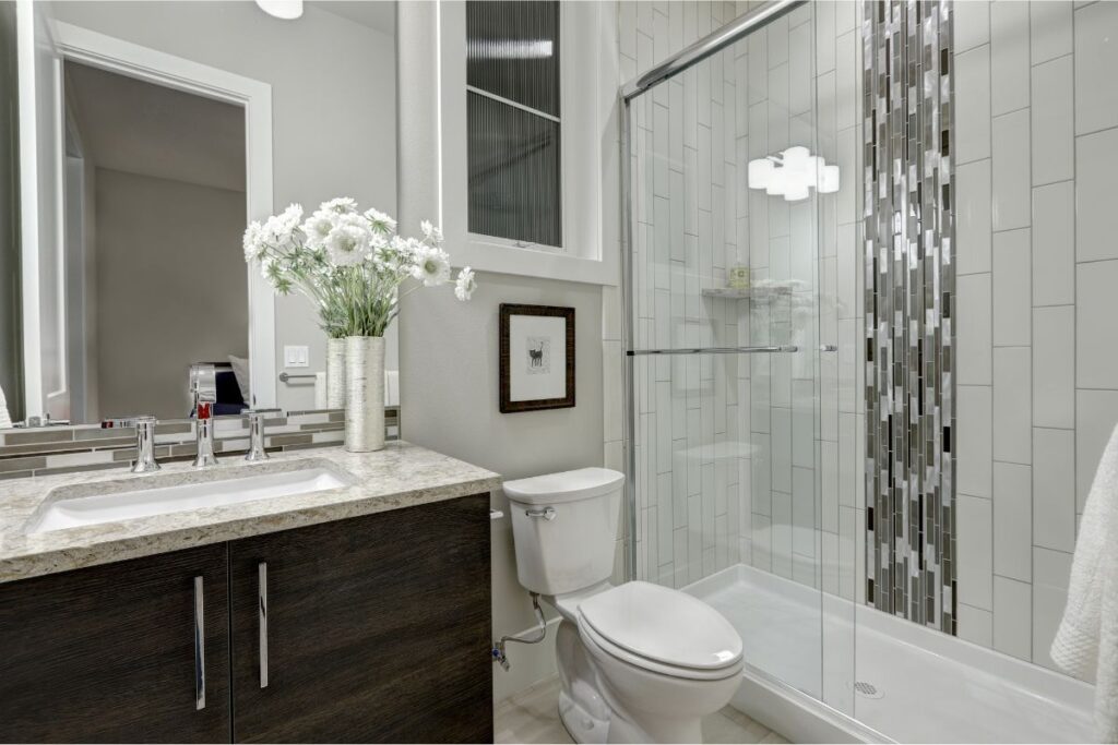 Shower stall in an Exeter, NH bathroom remodel with an acrylic shower base, tiled shower walls, and glass shower doors.