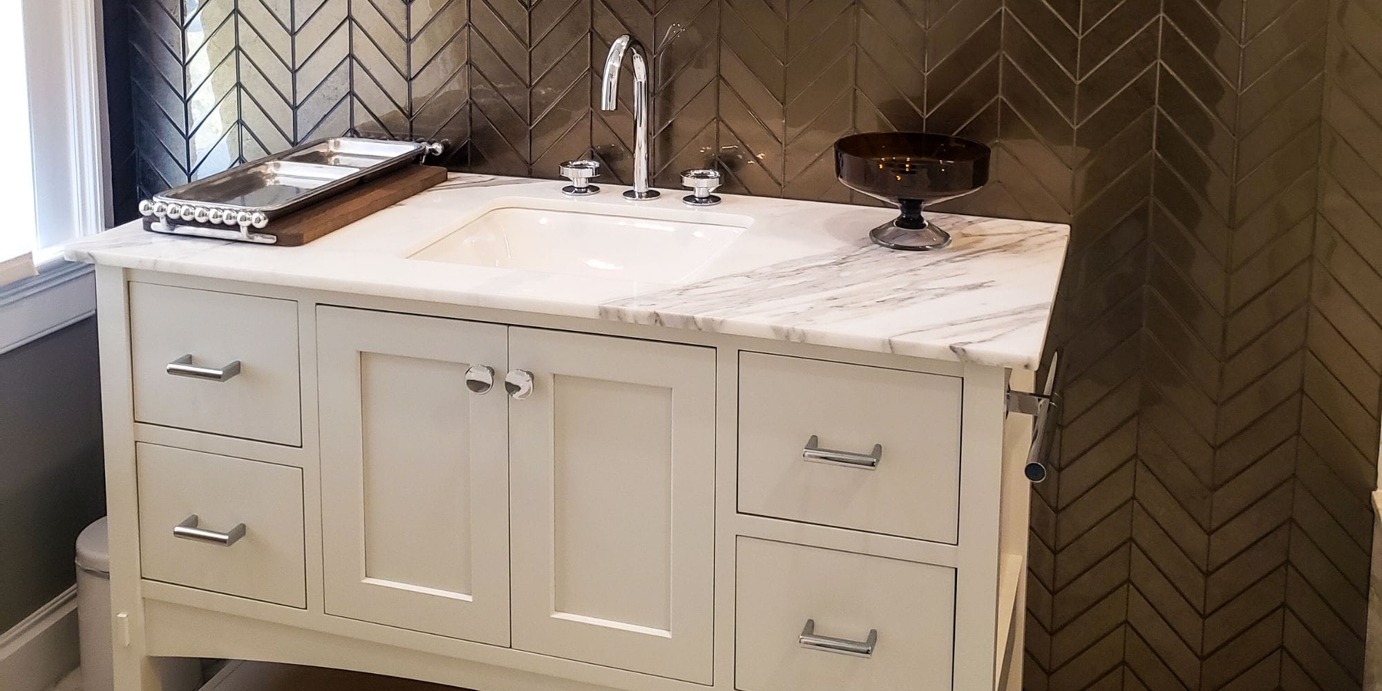 Luxury bathroom remodel with a high-end Kohler vanity, marble vanity top, and glass chevron tile accent wall in Rye, NH