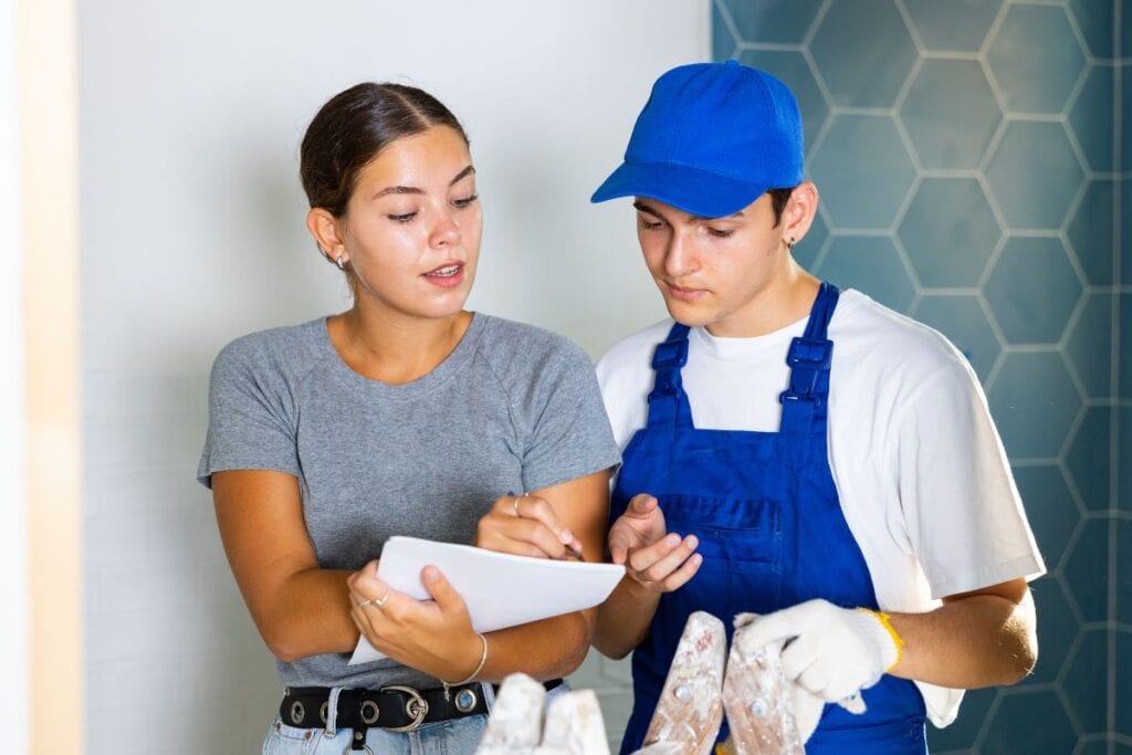 Young homeowner discusses an estimate with a contractor during a bathroom renovation.