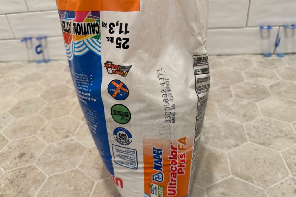 Bag of tile grout for a shower floor, with a lot number prominently displayed on the side of the bag